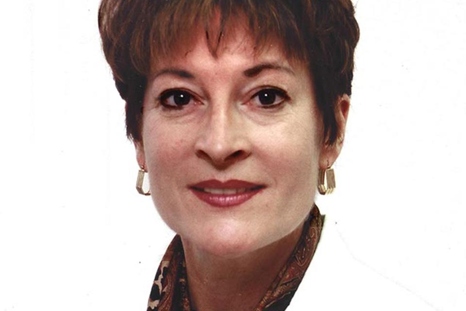 A woman wearing a doctor's white coat poses for a photo.