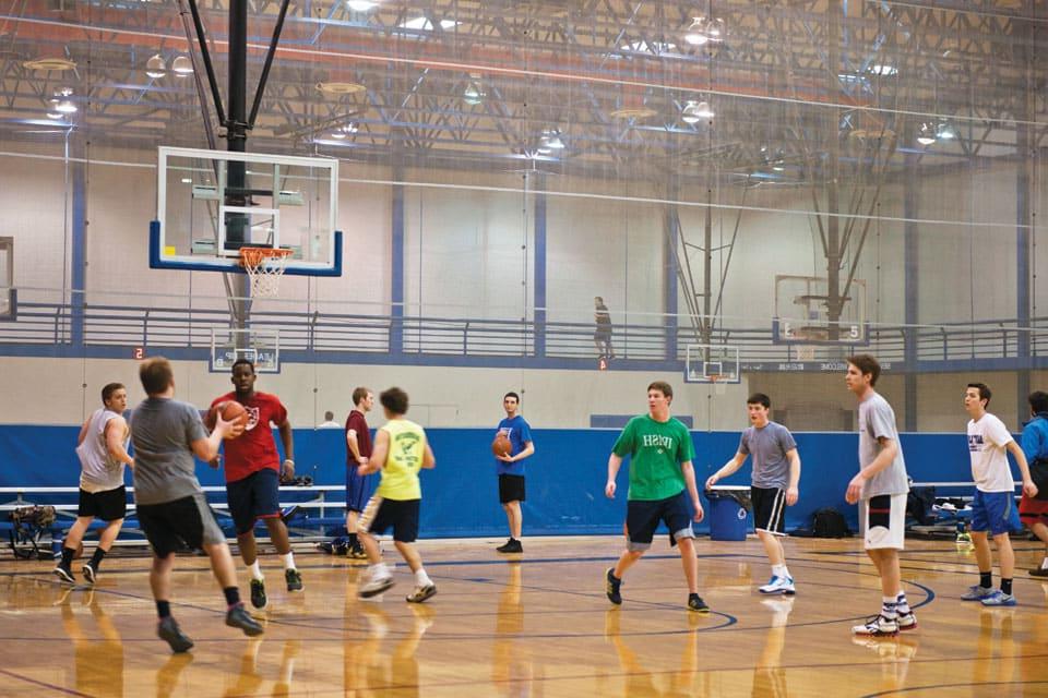 Students play basketball in a gymnasium.